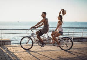 couple riding on tandem bicycle outdoors near the sea