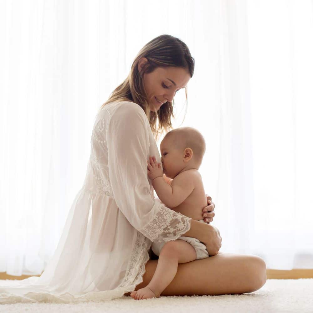 Young mother breastfeeding her newborn baby boy at home