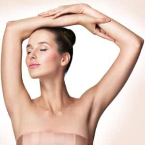 Beautiful young woman holding her arms up and showing clean underarms