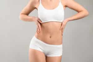 Woman in bra and underwear looking slim after liposuction