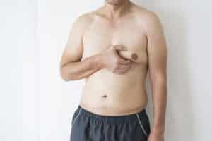 Man who has lost some weight, pinching excess skin and fat in chest area